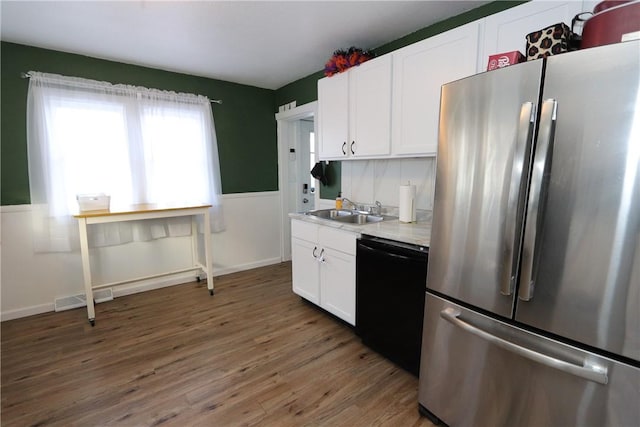 kitchen featuring sink, black dishwasher, dark hardwood / wood-style flooring, white cabinetry, and stainless steel refrigerator