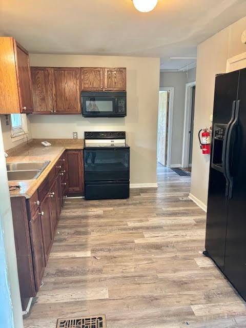 1414 14th St, Charleston, IL 61920 - kitchen with black appliances, a sink, light wood-type flooring, and light countertops