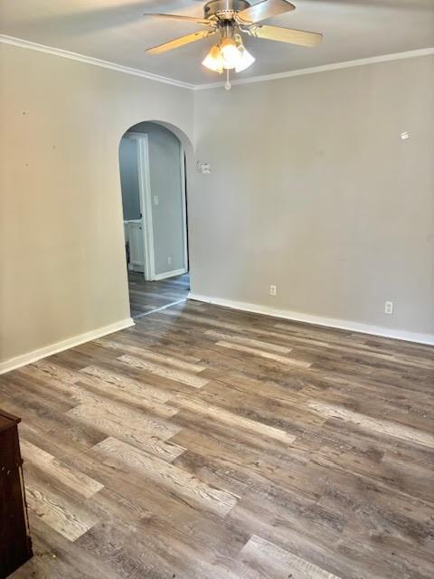 1414 14th St, Charleston, IL 61920 - empty room featuring arched walkways, crown molding, wood finished floors, baseboards, and a ceiling fan
