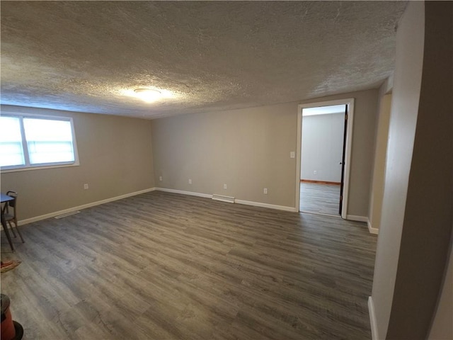 spare room featuring dark wood-style flooring, visible vents, a textured ceiling, and baseboards