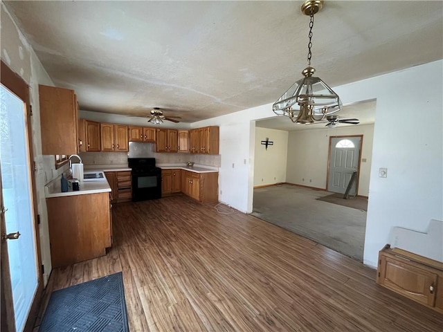 kitchen with black range oven, backsplash, decorative light fixtures, dark hardwood / wood-style flooring, and sink