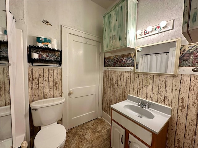 bathroom featuring vanity, toilet, and wooden walls