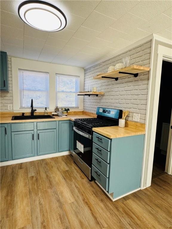 kitchen featuring sink, light hardwood / wood-style floors, stainless steel range with gas stovetop, and wooden counters