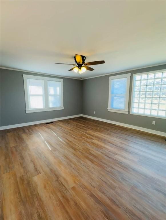 empty room featuring hardwood / wood-style floors, crown molding, and plenty of natural light