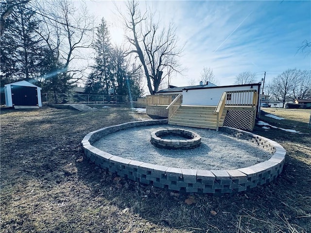 view of yard with a storage unit, a deck, and a fire pit