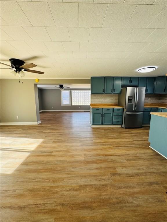 kitchen featuring butcher block counters, stainless steel fridge with ice dispenser, ceiling fan, and light wood-type flooring