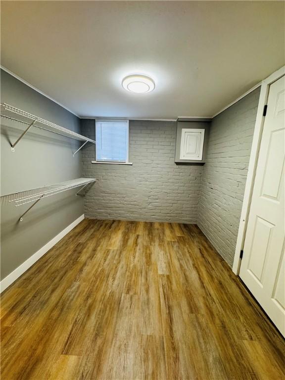 basement with wood-type flooring and brick wall