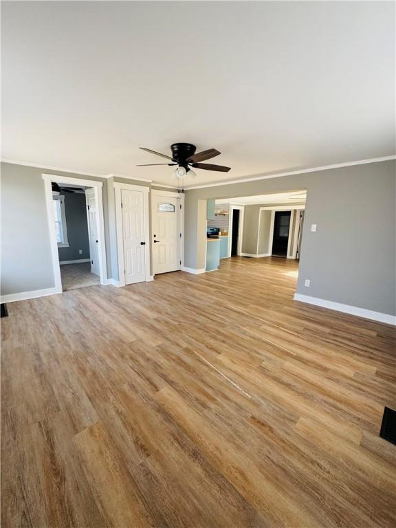 unfurnished living room featuring crown molding, ceiling fan, and light hardwood / wood-style floors