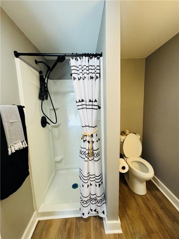 bathroom with toilet, hardwood / wood-style floors, and a shower with shower curtain