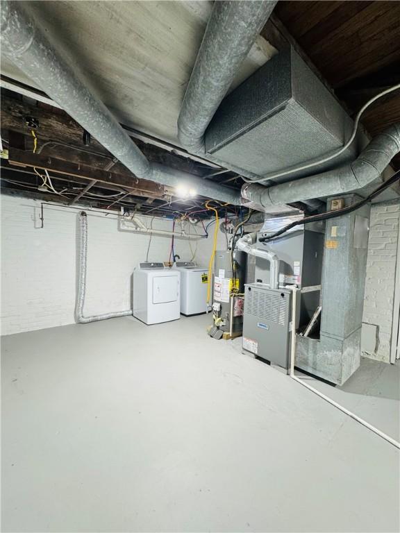 basement with heating unit, washer and dryer, and gas water heater