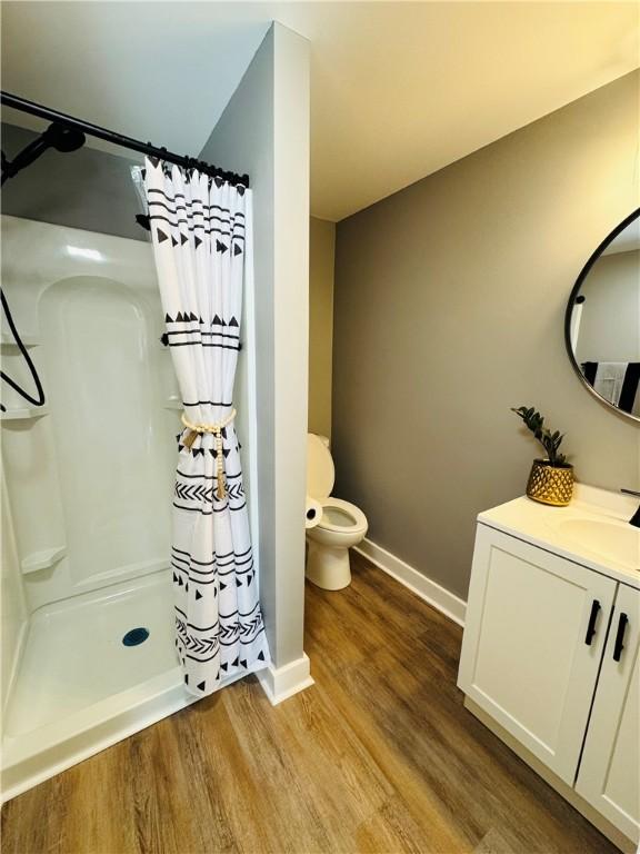 bathroom featuring vanity, curtained shower, wood-type flooring, and toilet