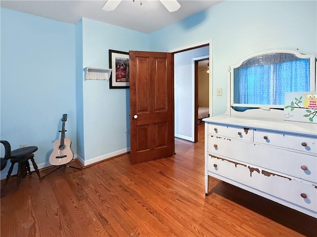 bedroom with light wood-style flooring, a ceiling fan, and baseboards