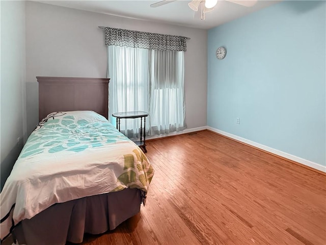 bedroom with baseboards, wood finished floors, and a ceiling fan