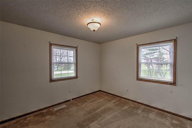 unfurnished room with baseboards, visible vents, carpet flooring, and a textured ceiling