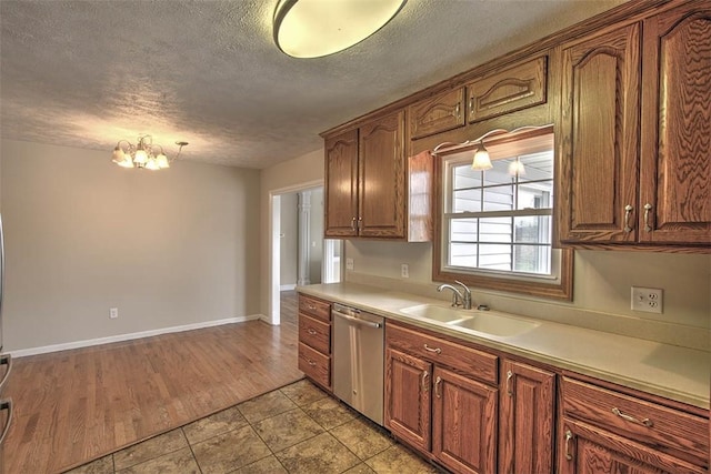 kitchen with light countertops, an inviting chandelier, a textured ceiling, a sink, and dishwasher