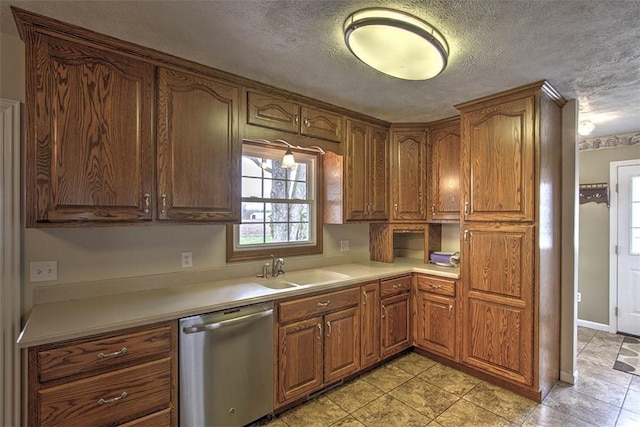 kitchen featuring a sink, light countertops, dishwasher, and a textured ceiling