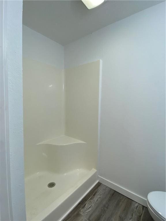 bathroom with toilet, walk in shower, and hardwood / wood-style floors