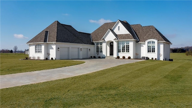 french country style house with a garage, driveway, a front lawn, and stucco siding