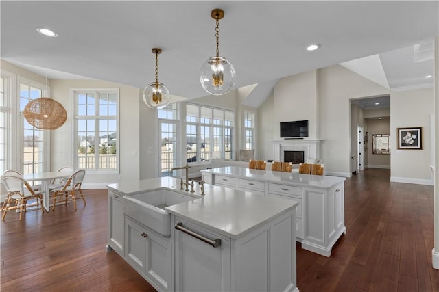 kitchen with white cabinets, an island with sink, open floor plan, light countertops, and a sink