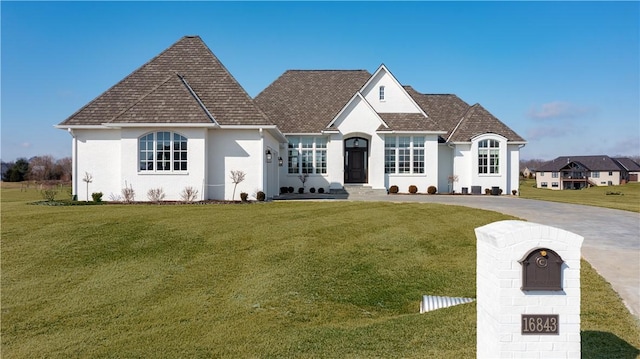 french provincial home featuring a front lawn and roof with shingles