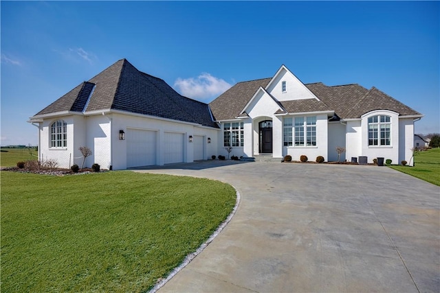 french provincial home with driveway, an attached garage, roof with shingles, and a front yard