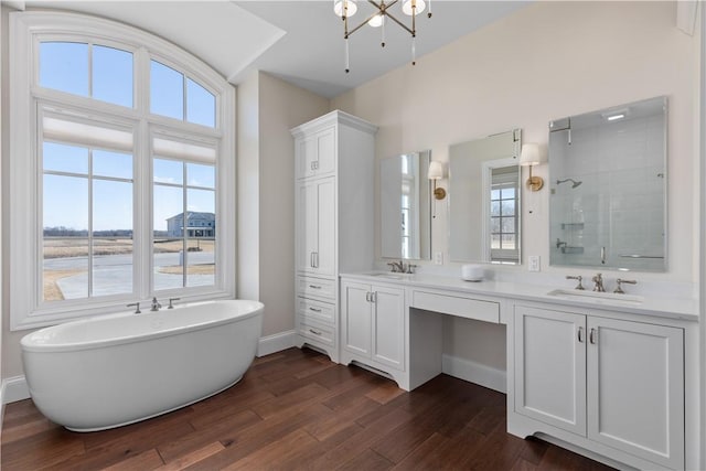 bathroom featuring double vanity, a sink, a freestanding bath, and wood finished floors