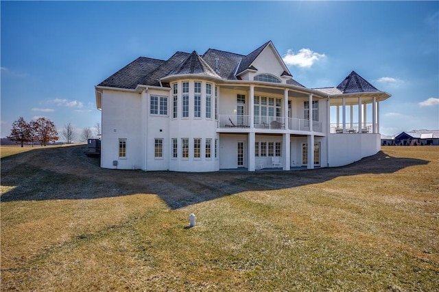 rear view of house with a lawn and a balcony