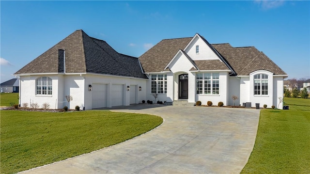 french country home featuring an attached garage, driveway, a front lawn, and stucco siding