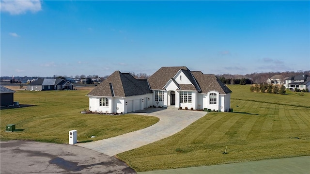 view of front of home featuring driveway, an attached garage, and a front lawn