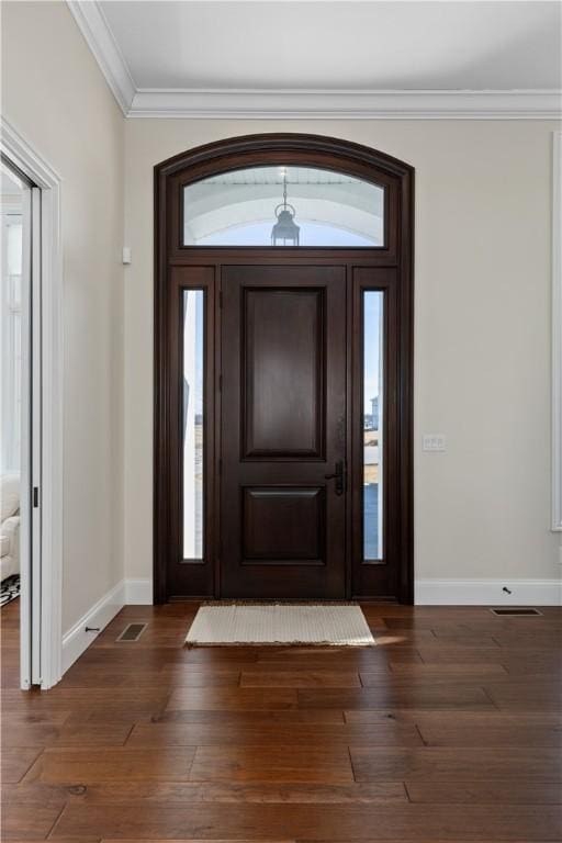 foyer with baseboards, visible vents, ornamental molding, and dark wood-style flooring