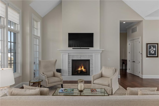 living area with high vaulted ceiling, dark wood-style flooring, a fireplace, visible vents, and baseboards