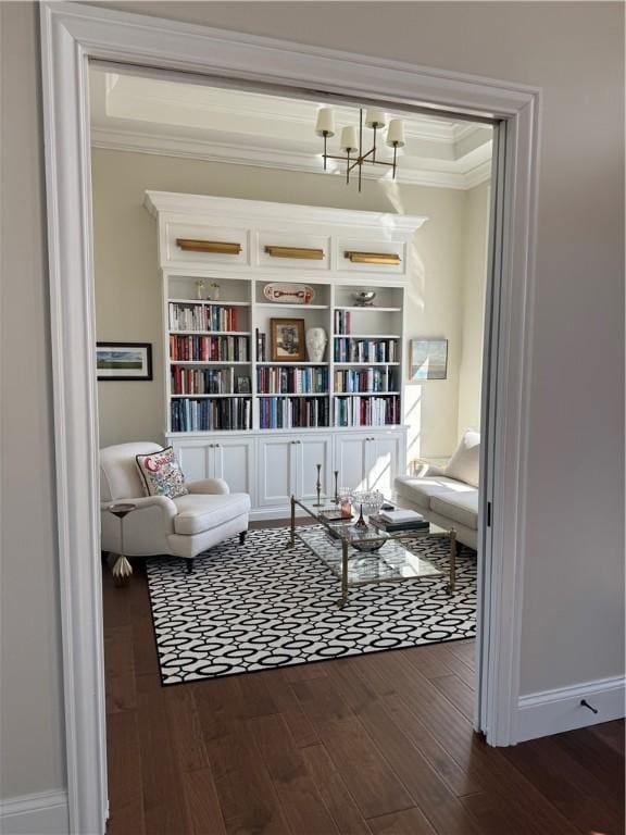 sitting room with baseboards, ornamental molding, dark wood-style flooring, and an inviting chandelier