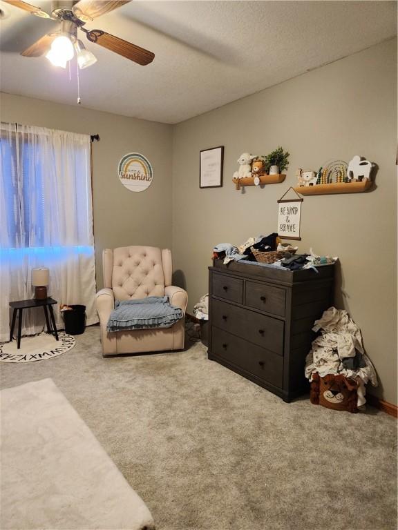 living area featuring carpet flooring and a ceiling fan