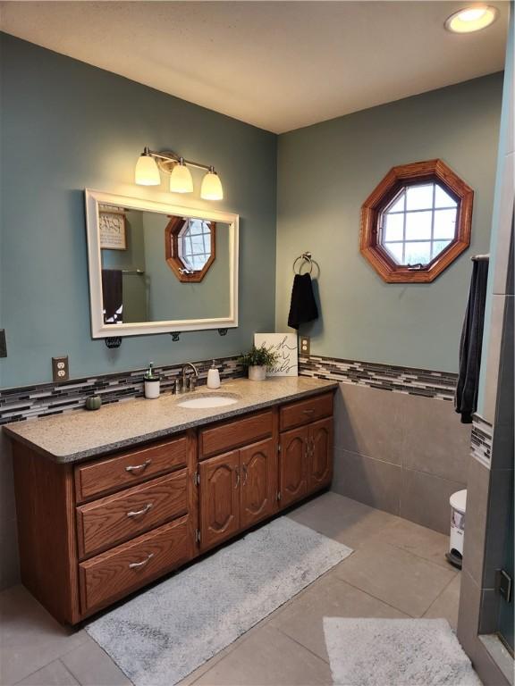 bathroom with tile patterned floors, tile walls, wainscoting, and vanity