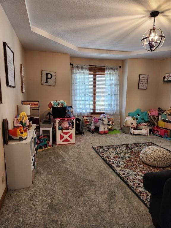 playroom featuring a notable chandelier, a textured ceiling, a tray ceiling, and carpet floors