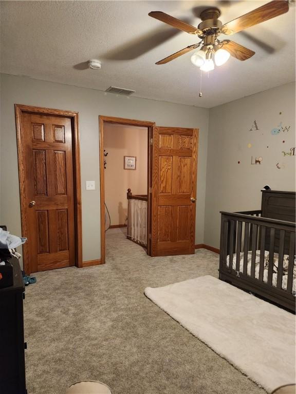 bedroom featuring visible vents, baseboards, carpet, and a textured ceiling