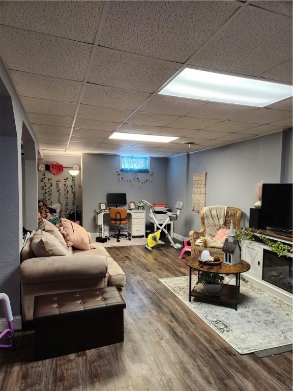 living area with wood finished floors, baseboards, and a paneled ceiling