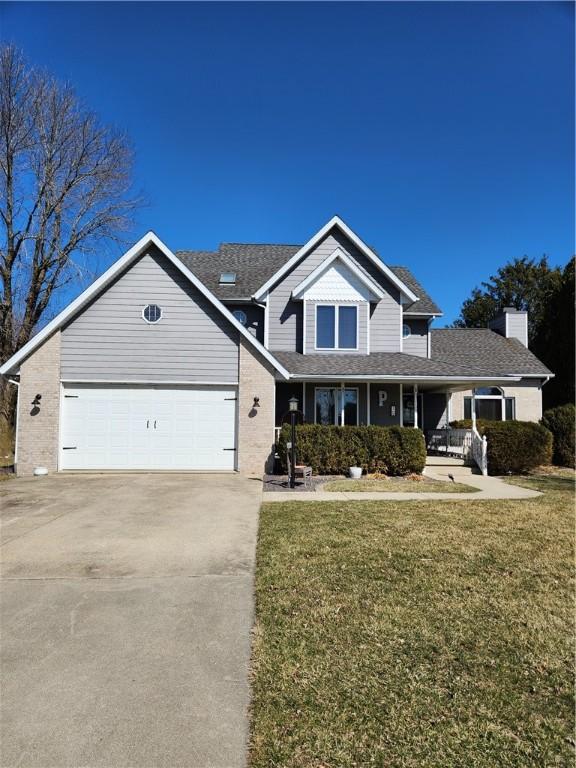 traditional home featuring a garage, a front lawn, a porch, and driveway