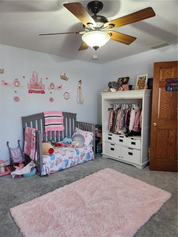 carpeted bedroom with a ceiling fan and visible vents