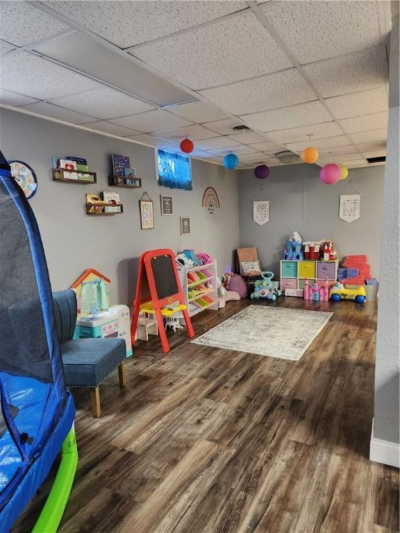 recreation room with a drop ceiling, baseboards, and wood finished floors