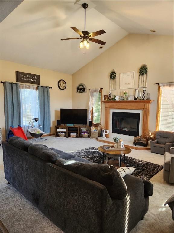 living room with a fireplace, high vaulted ceiling, ceiling fan, and carpet floors