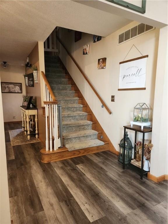 staircase with wood finished floors, visible vents, and baseboards