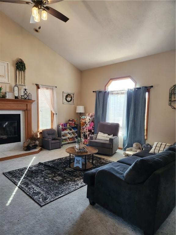 living area featuring a glass covered fireplace, high vaulted ceiling, a ceiling fan, and carpet floors