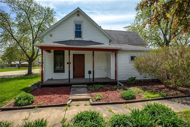view of front of house featuring covered porch, a front lawn, and roof with shingles