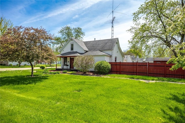 view of front facade featuring fence, a front lawn, and roof with shingles