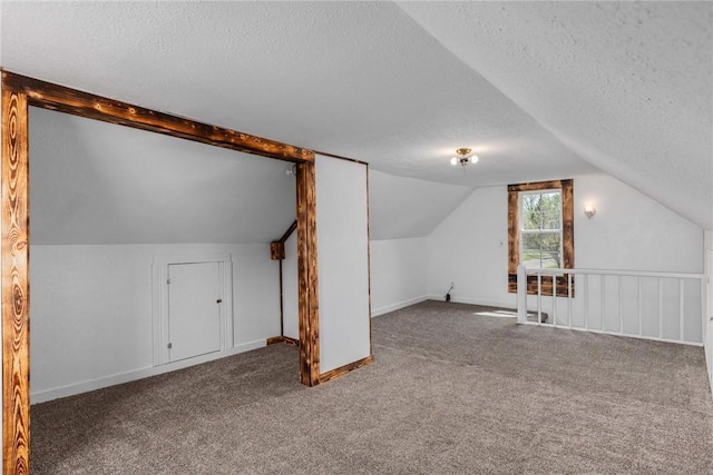 additional living space with baseboards, a textured ceiling, lofted ceiling, and carpet flooring