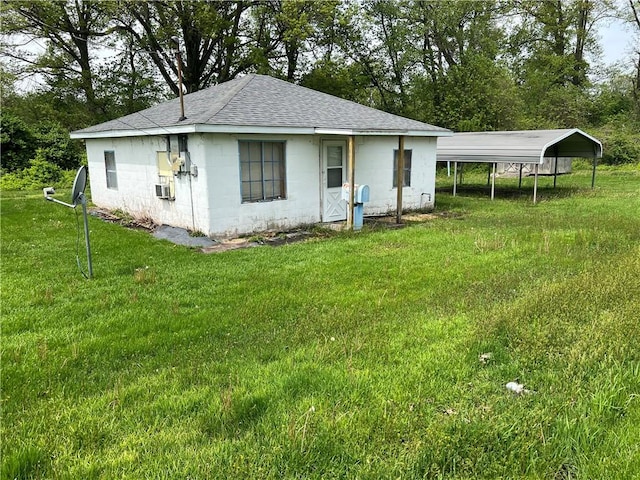 702 W Mulberry St, Robinson, IL 62454 - rear view of property featuring a lawn, a detached carport, a shingled roof, and concrete block siding