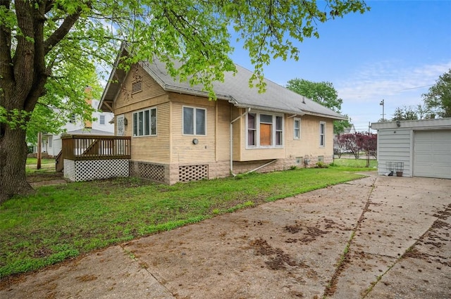 rear view of property featuring a lawn, a deck, and driveway
