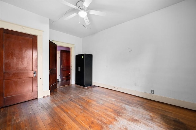empty room featuring a ceiling fan, baseboards, and wood-type flooring
