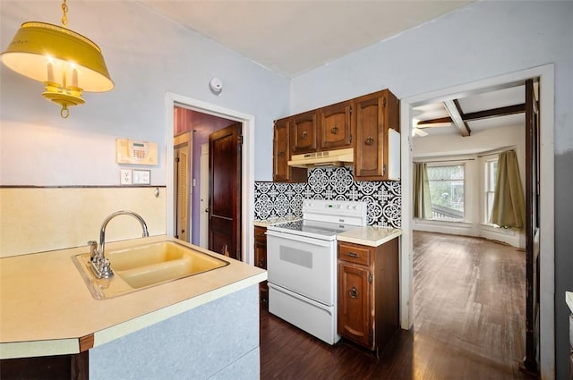 kitchen with a sink, white range with electric cooktop, under cabinet range hood, light countertops, and dark wood-style floors